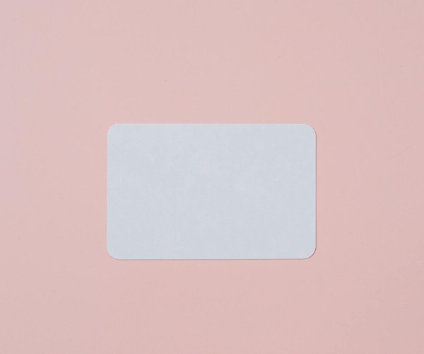 White visiting card with empty space for data placed on light pink background
